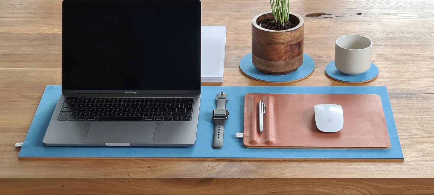 A tidy desk with a laptop on a blue felt mat